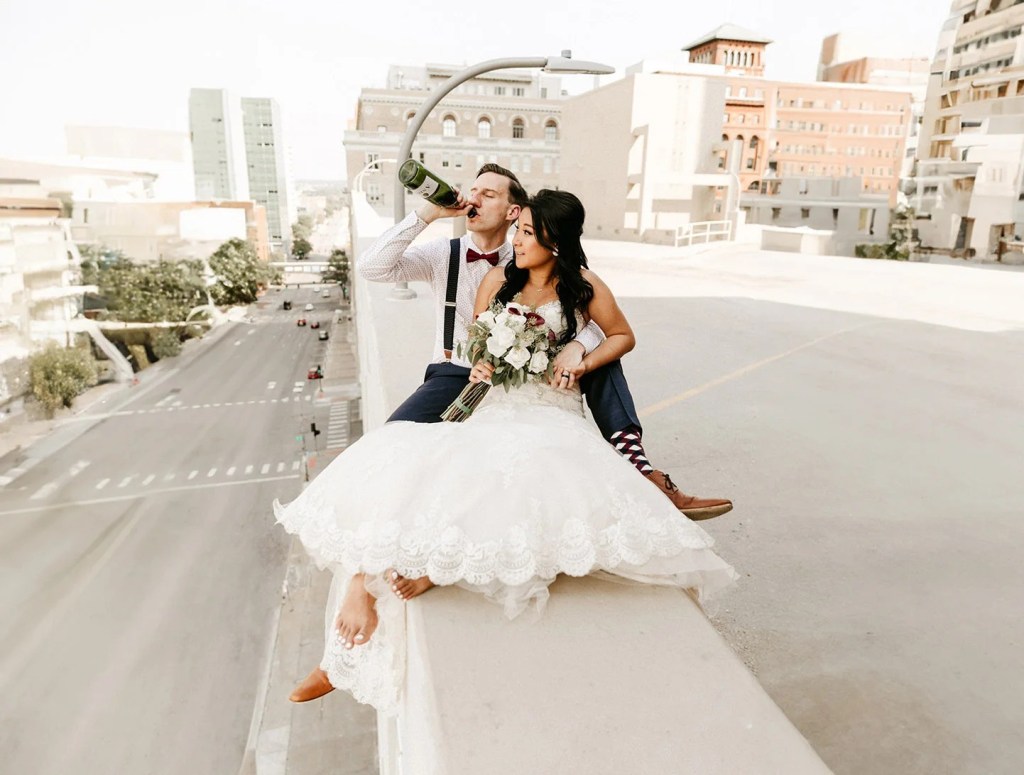 A beautiful couple sit on rooftop in los angeles and drinking wine